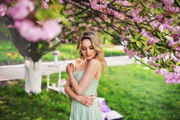 Frühling Schönheit Mädchen mit langen roten wehenden Haaren im Freien. blühender Sakura-Baum. romantisches Frauenporträt — Stockfoto