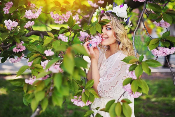 Vårens skönhet flicka med långa röda blåser håret utomhus. Blommande sakura träd. Romantiska ung kvinna porträtt — Stockfoto