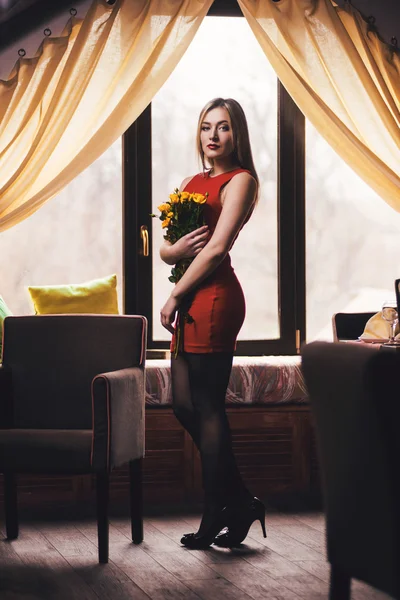 Junges schönes Mädchen in einem roten Kleid mit gelben Blumen — Stockfoto