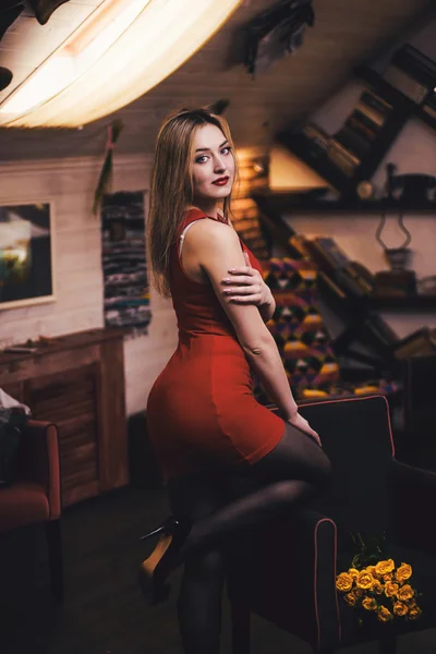 Fiatal gyönyörű lány, egy piros ruhás, a sárga virágok — Stock Fotó