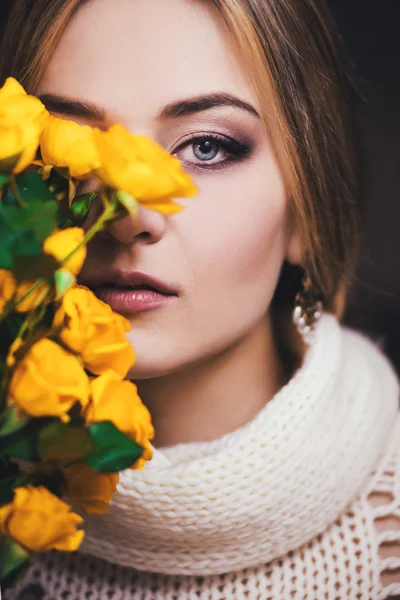 A közeli portré egy fiatal lány, sárga Rózsa közelében az arcát, sötét háttér előtt. Divat fotó. — Stock Fotó