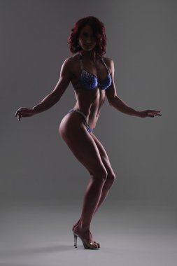 Karanlık studio arka planı, fitness bikini poz atletik genç kadın