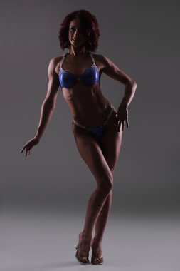 Karanlık studio arka planı, fitness bikini poz atletik genç kadın