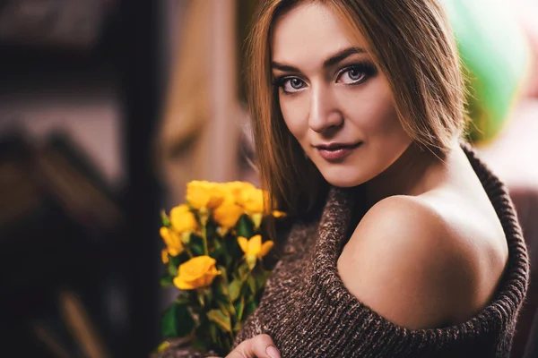 A close-up portrait of a young girl with yellow rose near her face, on dark background. Fashion photo. — Stock Photo, Image