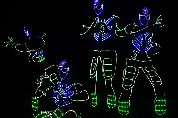 Tänzer in LED-Anzügen auf dunklem Hintergrund, farbige Show — Stockfoto