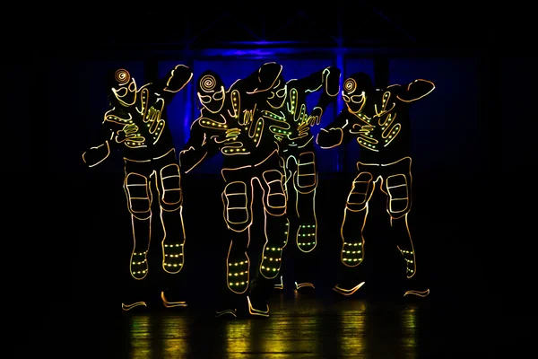 Tänzer in LED-Anzügen auf dunklem Hintergrund, farbige Show — Stockfoto