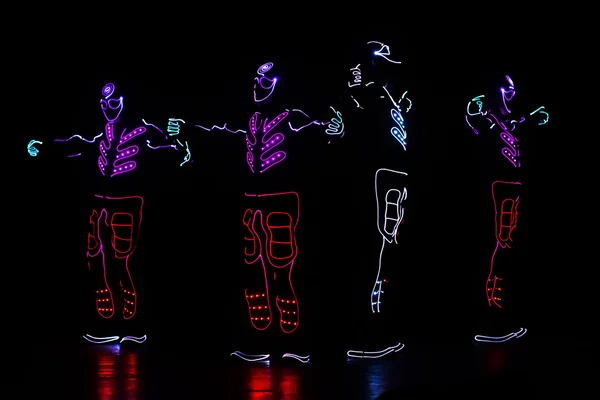 Танцоры в ведущих костюмах на темном фоне, цветное шоу — стоковое фото