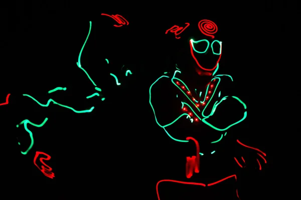 Tänzerbesatzung in LED-Anzügen auf dunklem Hintergrund, farbige Show — Stockfoto