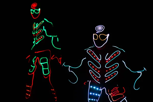 Bailarines tripulación en trajes led sobre fondo oscuro, espectáculo de color — Foto de Stock