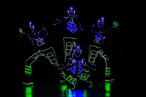 Dançarinos em ternos led no fundo escuro, show colorido — Fotografia de Stock