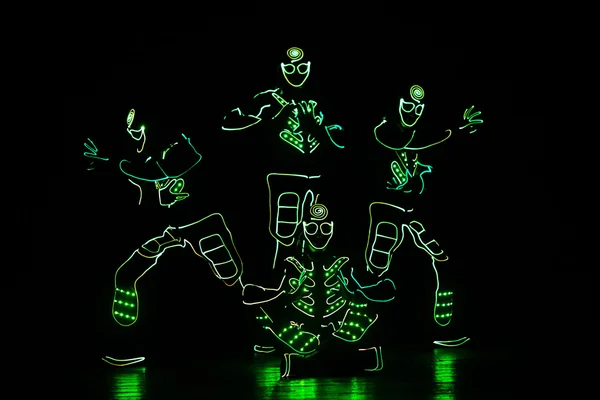 Bailarines en trajes led sobre fondo oscuro, espectáculo de colores — Foto de Stock