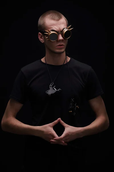 Tatuagem artista em óculos com espinhos segurando máquina de tatuagem no fundo escuro, conceito de tatuagem — Fotografia de Stock