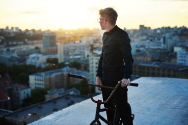 Gün batımında Bisiklet cityscape ile poz binici