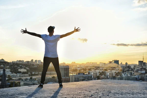 Glücklicher Mann mit erhobenen Händen bei Sonnenuntergang. Mit offenen Armen steht er barfuß auf einem Steg. Sonne genießen. Sonne im Blick. — Stockfoto