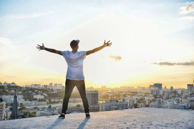 adam bir kentin silueti günbatımında karşı karşıya Kollarını açarak