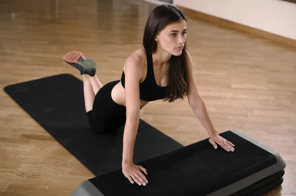 Wunderschöne und starke Brünette macht eine Reihe von Liegestützen in einem Fitnessstudio — Stockfoto