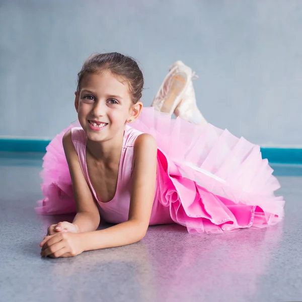 Junge Ballerina in pinkfarbenen Kleidern sitzt während des Tanzkurses auf dem Boden. — Stockfoto