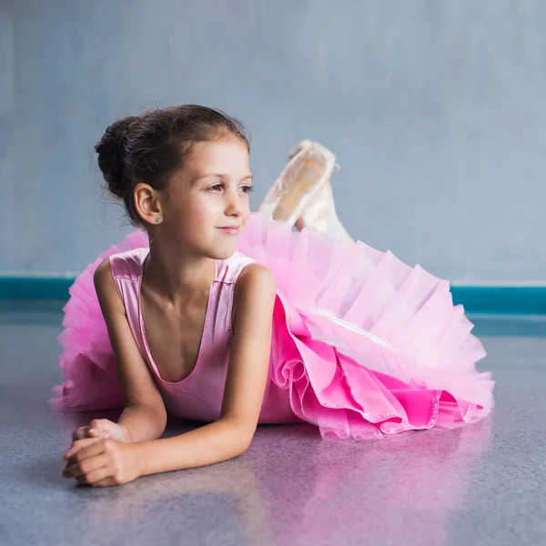 Junge Ballerina in pinkfarbenen Kleidern sitzt während des Tanzkurses auf dem Boden. — Stockfoto