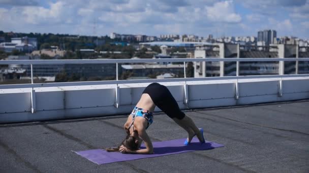 Красивая спортивная девушка делает упражнения пилатес и йога на крыше — стоковое видео