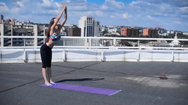 Mujer haciendo ejercicios de yoga y pilates en el techo del rascacielos de la ciudad — Vídeo de stock