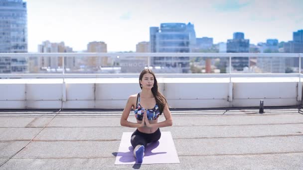 Mujer haciendo ejercicios de yoga y pilates en el techo del rascacielos de la ciudad — Vídeo de stock