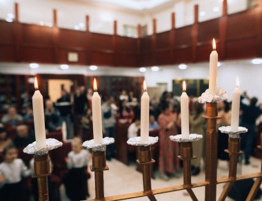 Bulanık sinagog arka planıyla odak noktasında Hanuka mumları yakmak. Sıcak atmosfer ve Yahudi bayramı geleneği.