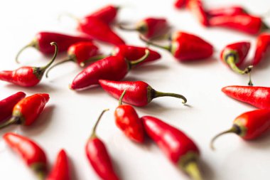 Beyaz arka planda yatan kırmızı biberler taze, baharatlı ve evde yetişen acı biberleri sembolize eder..