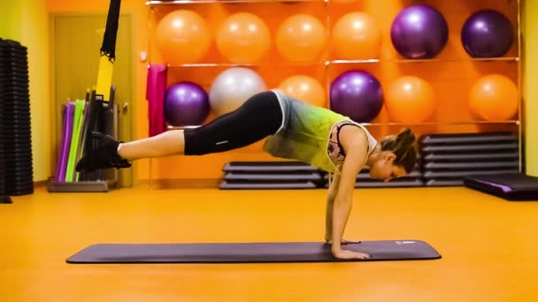 Jonge aantrekkelijke vrouw training met htrx fitness bandjes in de sportschool studio — Stockvideo
