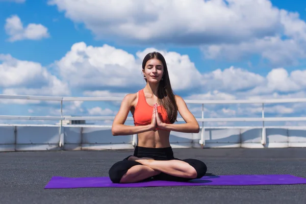 Jóga és a meditáció egy modern műépítészeti város. Fiatal, vonzó lány - jóga meditál, modern felhőkarcolók ellen — Stock Fotó