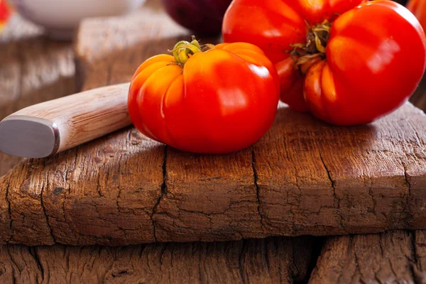 Closeup of a beef tomato and kitchen knife — Stock Photo, Image