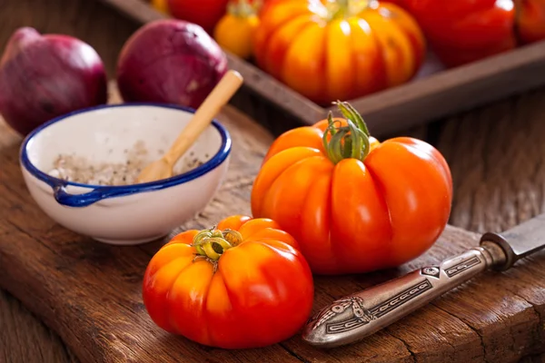 Tomates de vaca maduros com uma faca, cebolas e sal — Fotografia de Stock