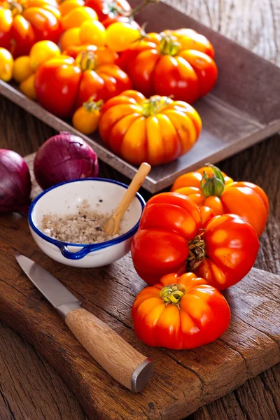 Beef tomatoes, salt bowl with spoon and a knife — Stock Photo, Image