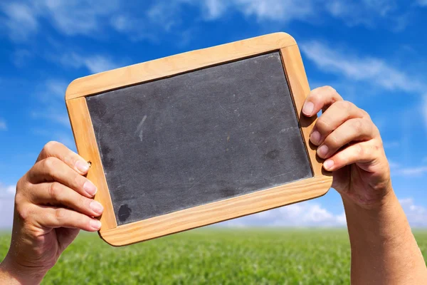 Hände halten eine Schiefertafel mit Werbefläche — Stockfoto