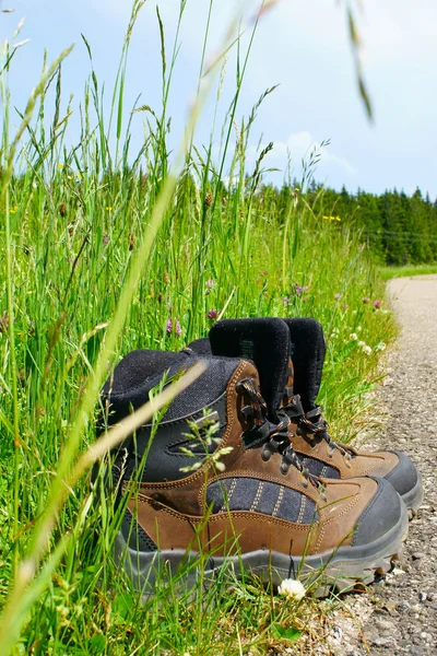 Botas de caminhada ficam na beira da estrada — Fotografia de Stock