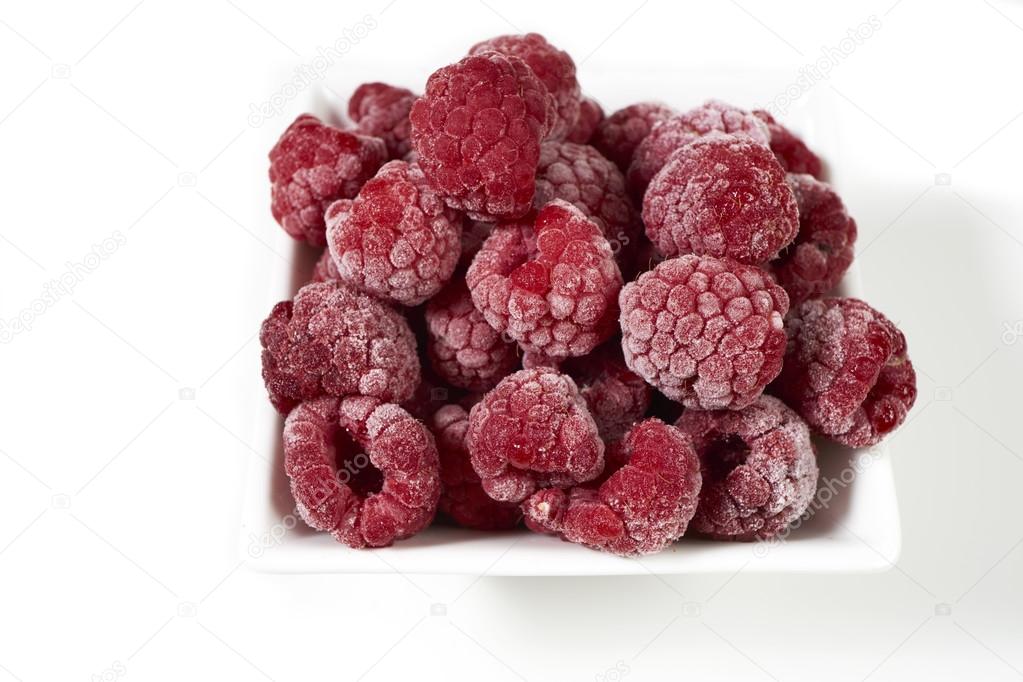 Frozen raspberries in a white porcelain dish