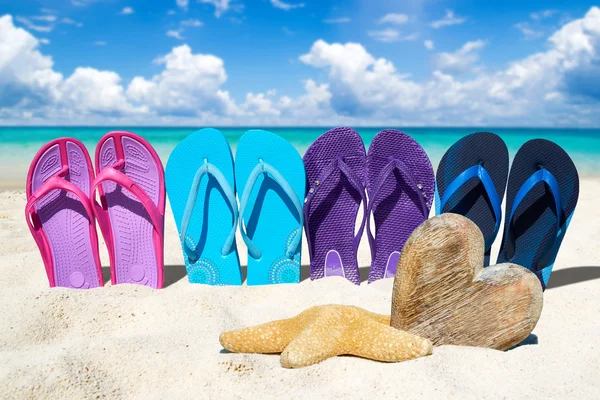 Slippers en houten hart op het strand — Stockfoto