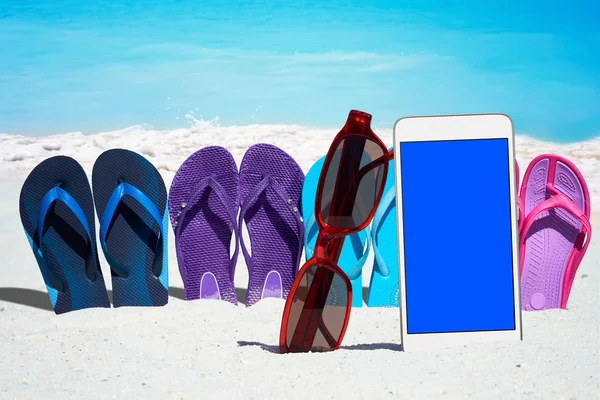 Smartphone i klapki japonki na plaży — Zdjęcie stockowe