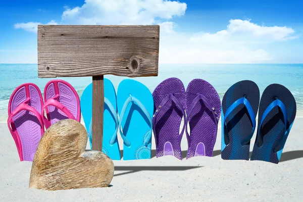 Wooden heart and flip flops on beach — Stock Photo, Image