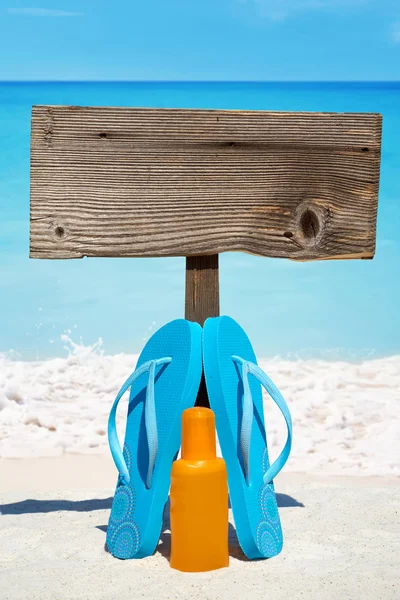 Placa de madeira e chinelos na praia — Fotografia de Stock