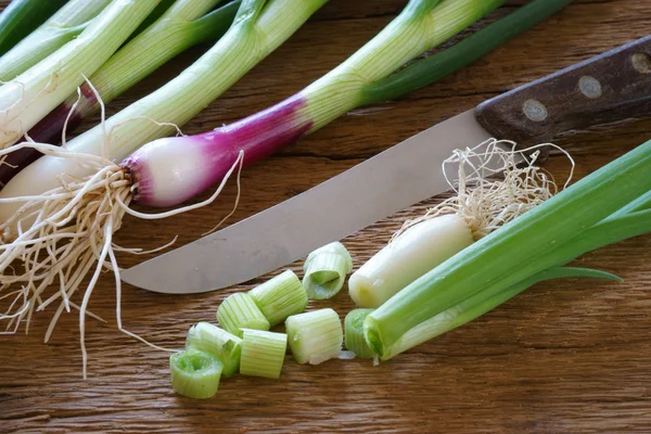 Cebollas y cuchillo en tabla de cortar — Foto de Stock