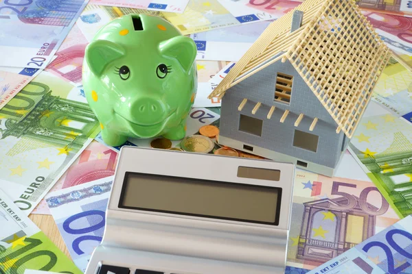 Piggy Bank and Pocket calculator on banknotes — Stock Photo, Image