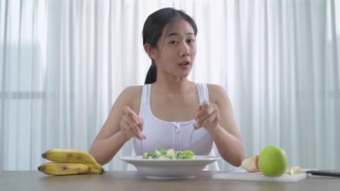 Sağlık konsepti. Asyalı bir kadın ev yapımı sebze salatası yapmak için röportaj yapıyor. 4k Çözünürlüğü.