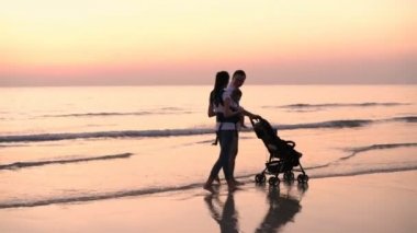 Aile kavramı. Ebeveynler ve çocuklar sahilde mutlu bir şekilde yürüyorlar. 4k Çözünürlüğü.