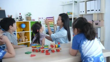 Eğitici kavramlar. Öğretmen sınıfta anaokulu çocukları için abaküs ile matematik öğretiyor. 4k Çözünürlüğü.
