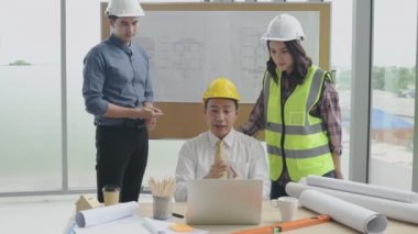 İş konsepti. Asyalı mühendislik ekibi çalışmayı bir ofis bilgisayarı aracılığıyla sunuyor. 4k Çözünürlüğü.