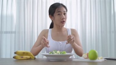 Sağlık konsepti. Asyalı bir kadın ev yapımı sebze salatası yapmak için röportaj yapıyor. 4k Çözünürlüğü.