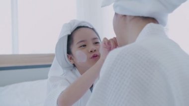Spa konsepti 4k Çözünürlük. Annem yatak odasındaki kızına yüz maskesi takıyor..