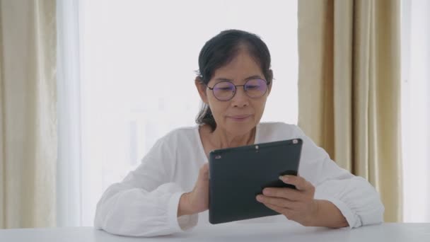 4K解像度の休日の概念 アジアの高齢女性は技術に興味があり 家の中でタブレットを使用しています — ストック動画