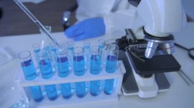 Araştırma konsepti 4K çözünürlüğü. Bir bilim adamı deney tüpüne sıvı damlatıyor..