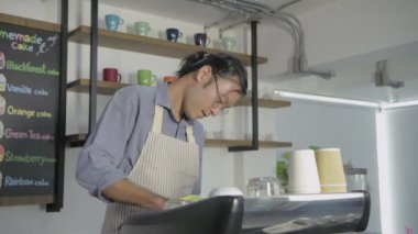 Kafe konsepti 4k Kararlılık. Asyalı bir erkek çalışan dükkanı temizliyor..
